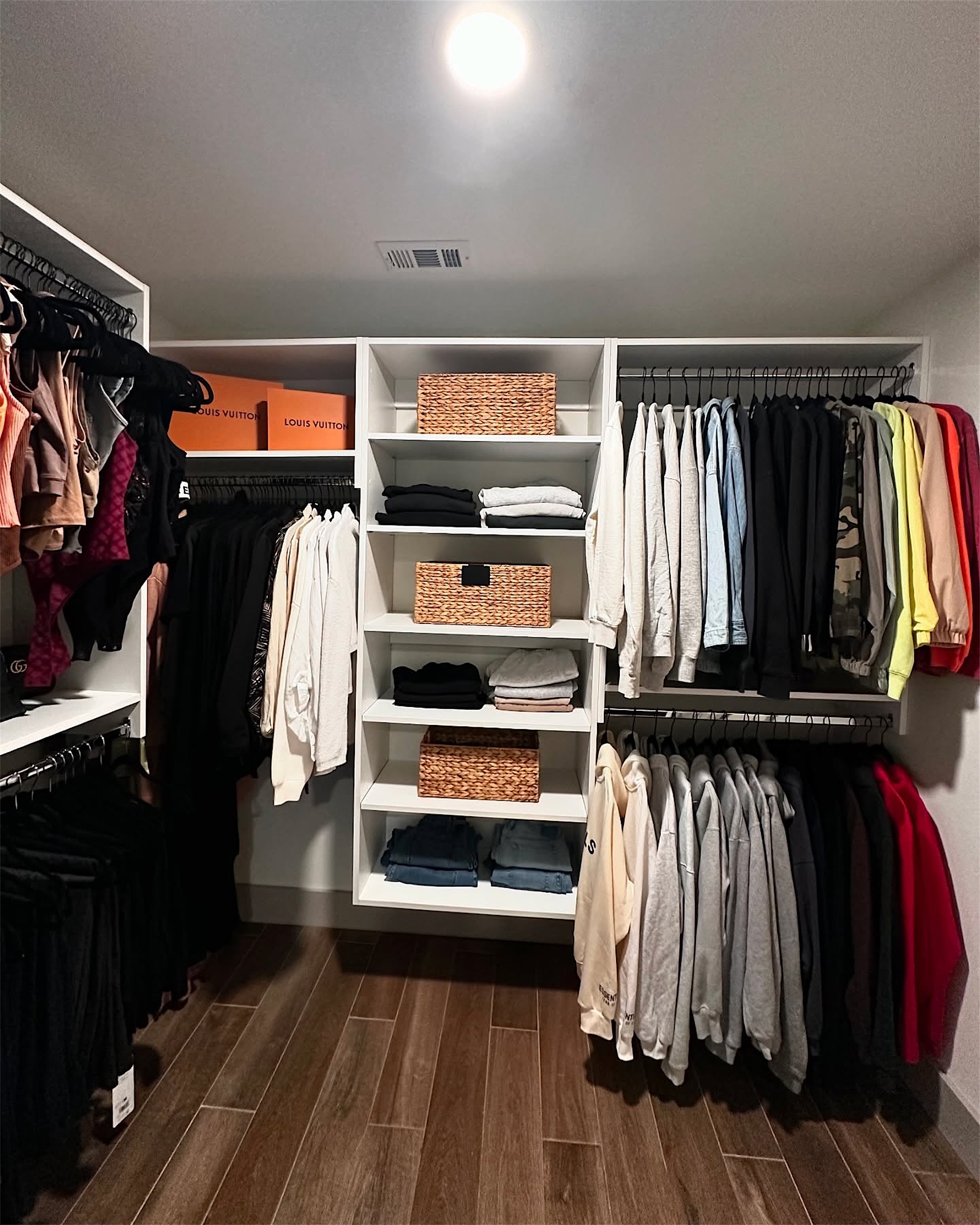 A walk-in closet with woven baskets, folded stacks and hanging in order